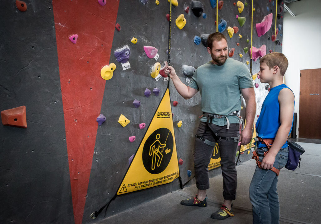son and father at a rock climbing gym using perfect descent auto belays